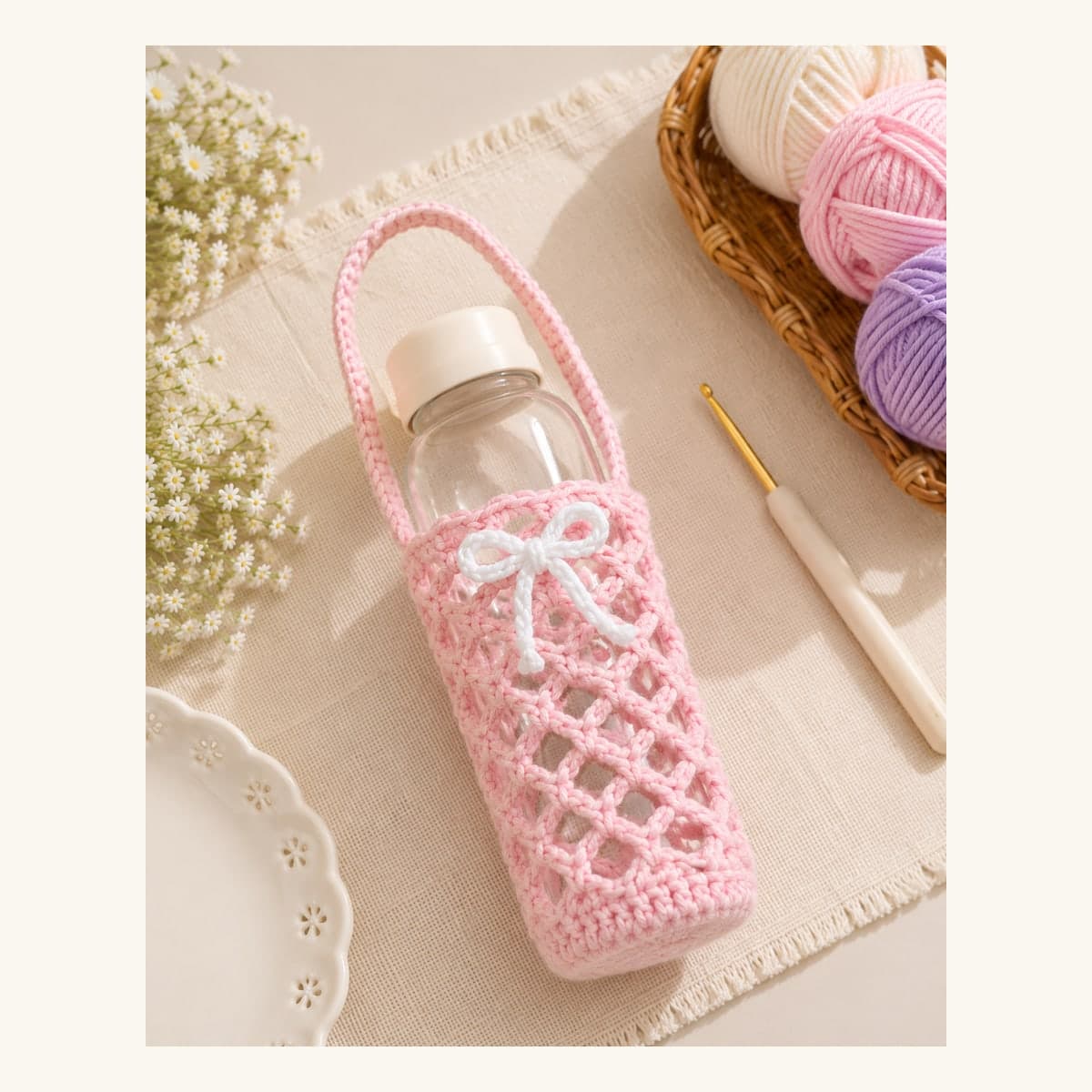Handmade blush-pink crochet bottle holder with strap and bow detail.